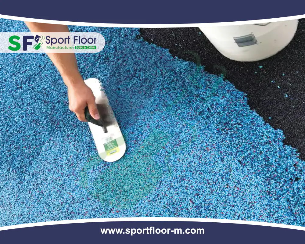 Blue rubber granule sports surface being applied with a hand trowel
