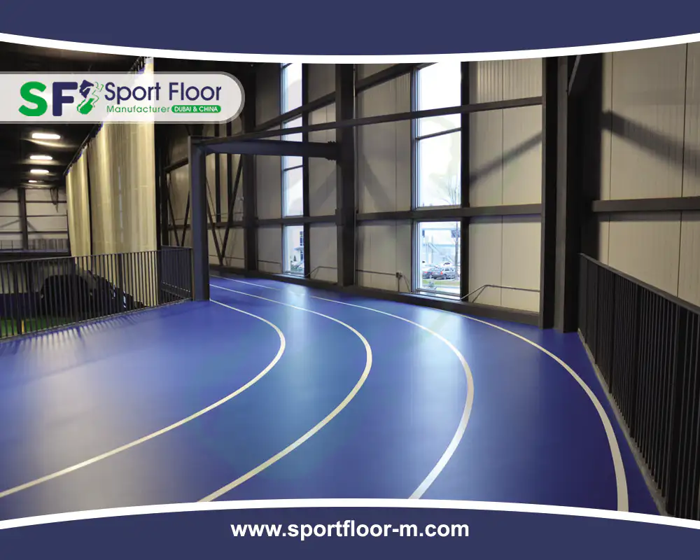 Curved blue indoor running track with guardrails and lane markings
