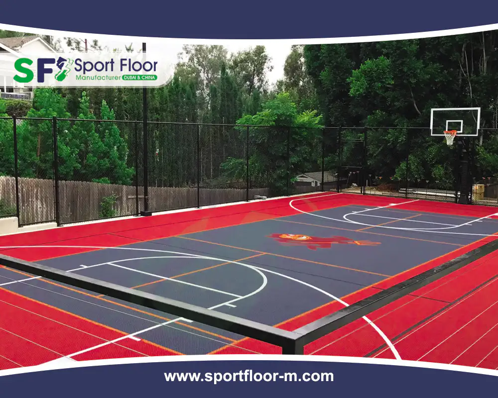 Red and grey outdoor basketball court with perimeter drainage and fencing