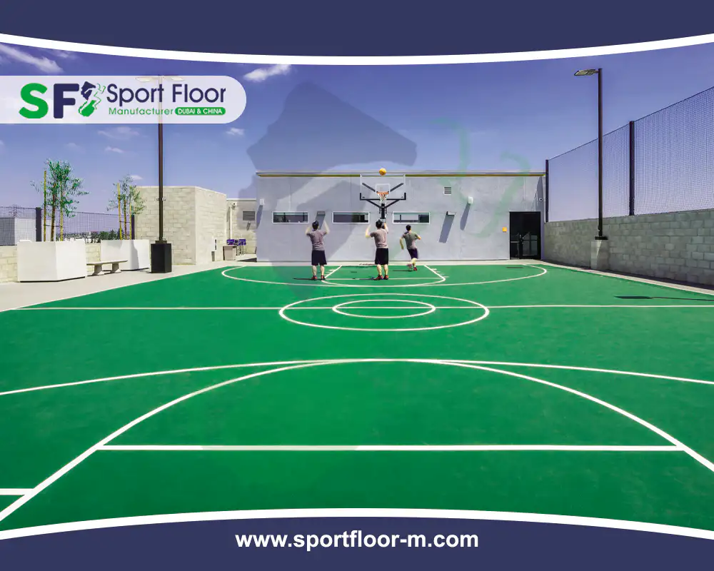 Outdoor green basketball court with players and perimeter fencing
