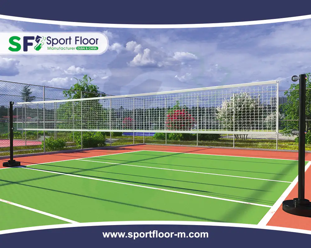 Green outdoor acrylic volleyball court with red surrounding zone and net posts