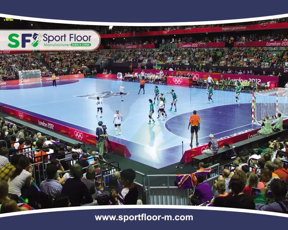 Indoor handball match on a blue sports surface with marked goal areas