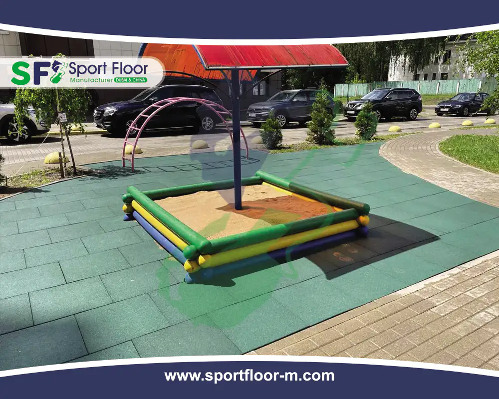 Green rubber tiles installed around a playground sandbox